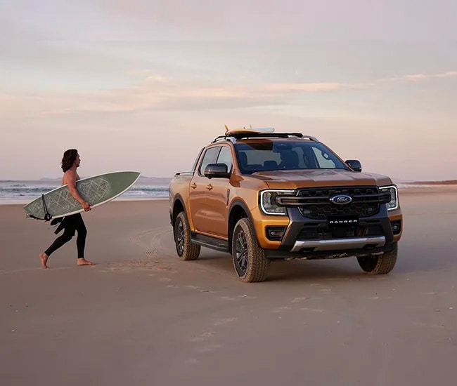 Man walking toward his Ford Ranger parked on the beach