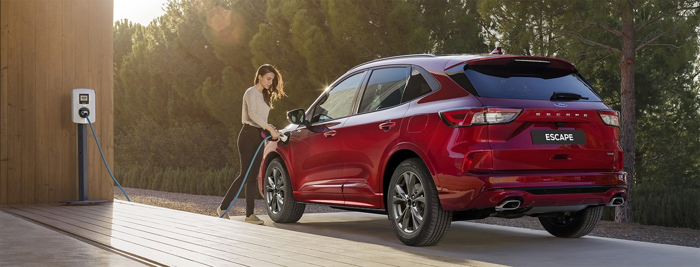 Woman charging a red Ford Escape PHEV at home