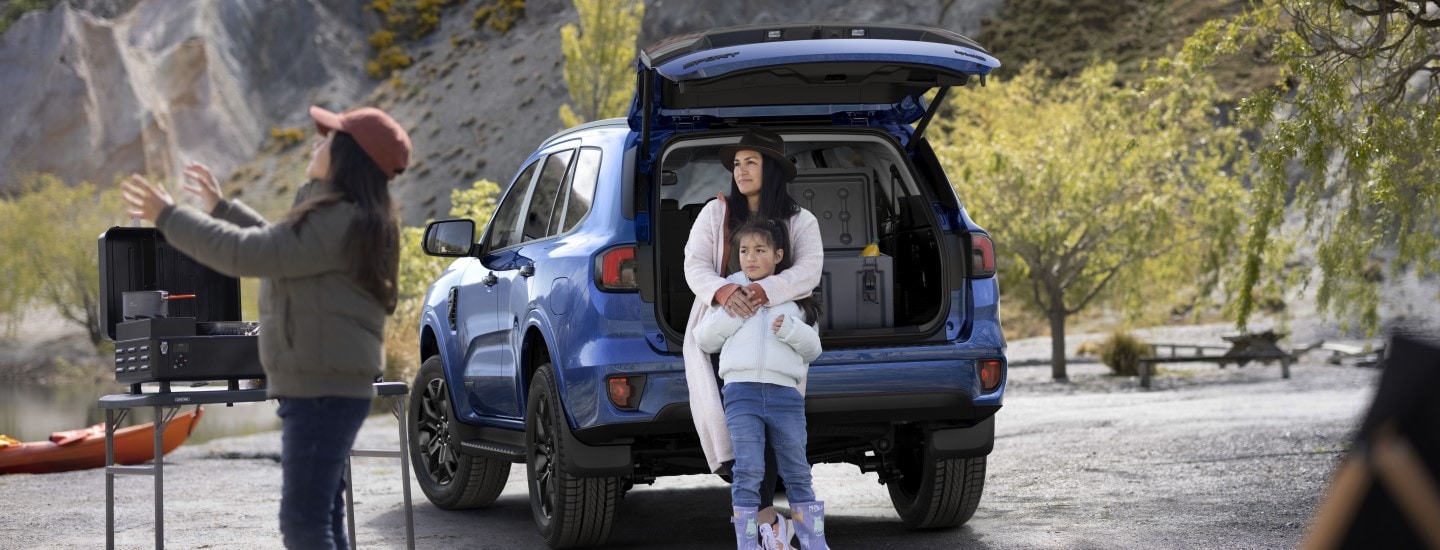 Red Ford Everest parked off road on a hill with two hikers